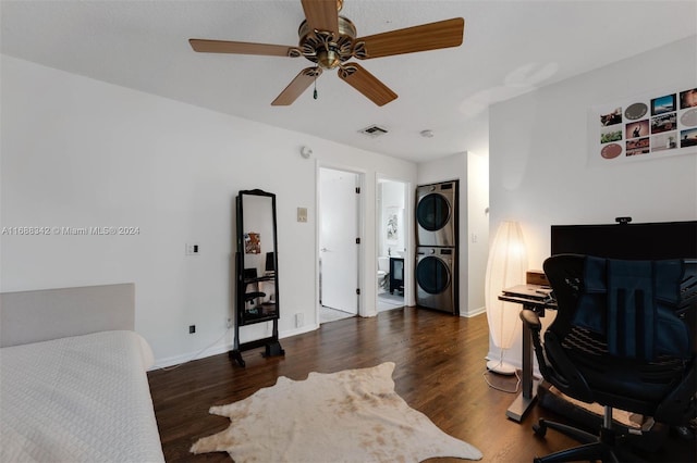 bedroom featuring stacked washer / drying machine, dark hardwood / wood-style flooring, and ceiling fan