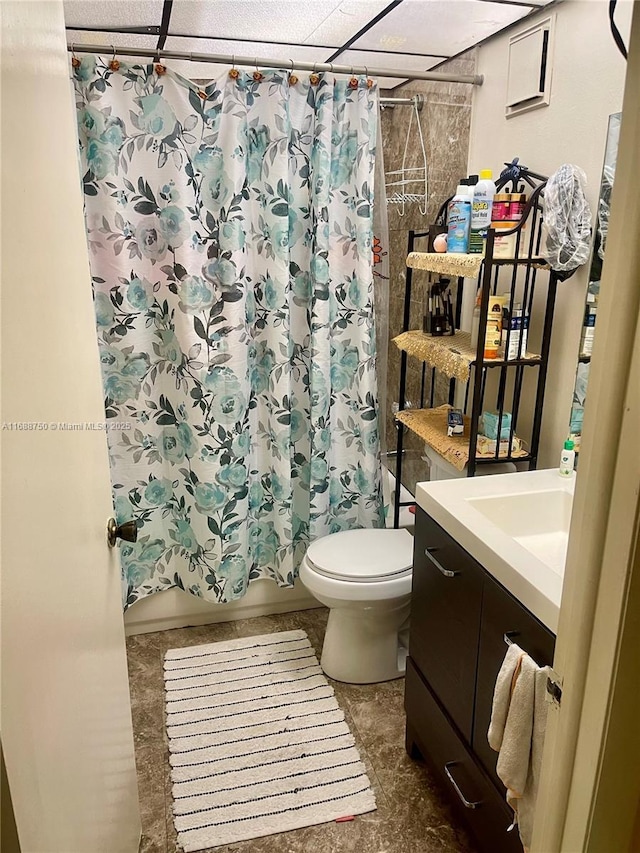 full bathroom featuring a drop ceiling, vanity, shower / bath combo, and toilet