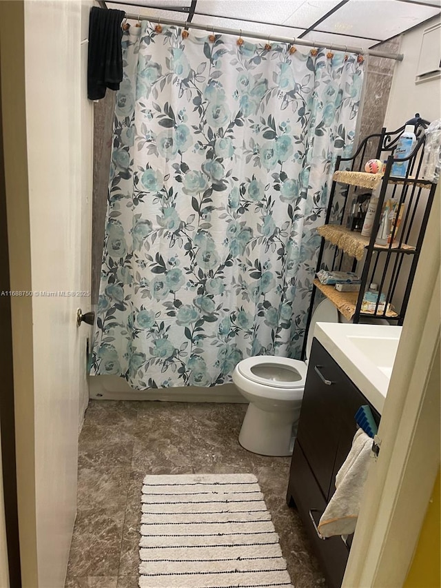 full bathroom with a paneled ceiling, shower / bath combo, toilet, and vanity