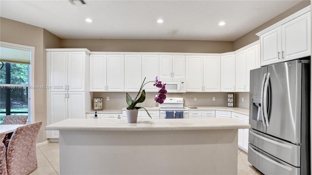 kitchen with a center island with sink, light tile patterned flooring, white cabinets, and white appliances