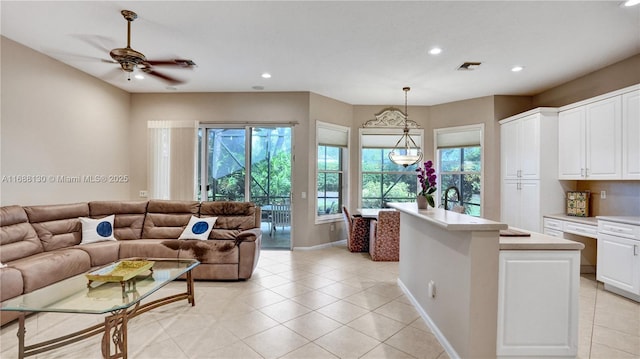 interior space featuring pendant lighting, white cabinetry, ceiling fan, and an island with sink