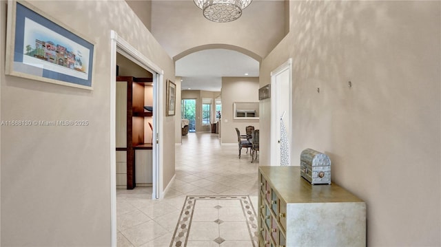 hall featuring light tile patterned floors and an inviting chandelier