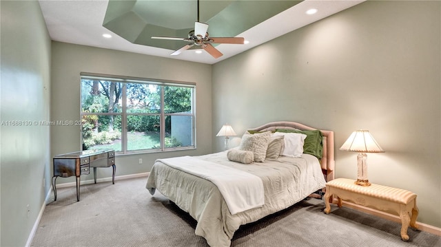 bedroom featuring a raised ceiling, ceiling fan, and light colored carpet