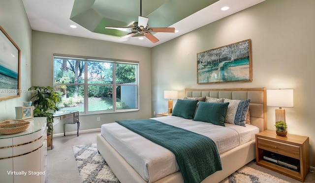 bedroom with light colored carpet, ceiling fan, and a tray ceiling