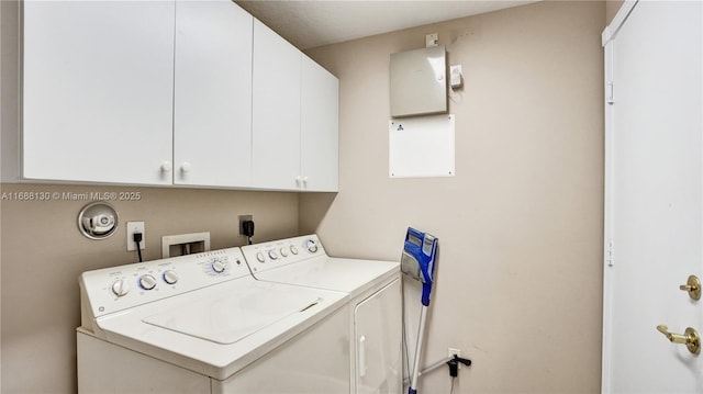 laundry room with washing machine and clothes dryer and cabinets