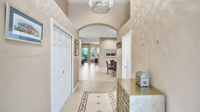 hallway with a chandelier and light tile patterned floors