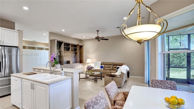 kitchen featuring white cabinets, a center island with sink, stainless steel refrigerator, and sink