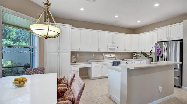 kitchen featuring white appliances, sink, white cabinets, hanging light fixtures, and an island with sink