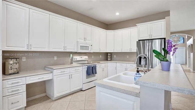 kitchen with sink, light tile patterned floors, an island with sink, white appliances, and white cabinets