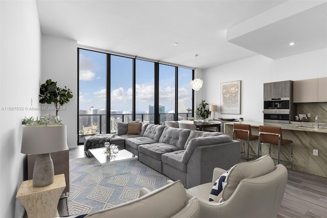 living room with light wood-type flooring, an inviting chandelier, floor to ceiling windows, and sink