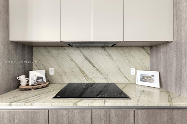 room details featuring decorative backsplash, ventilation hood, and black electric cooktop