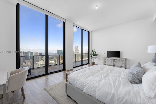 bedroom with access to exterior, light hardwood / wood-style floors, and a wall of windows