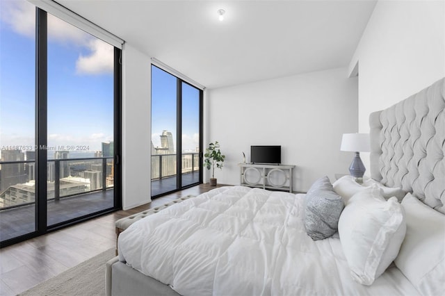 bedroom featuring access to exterior, expansive windows, and hardwood / wood-style flooring