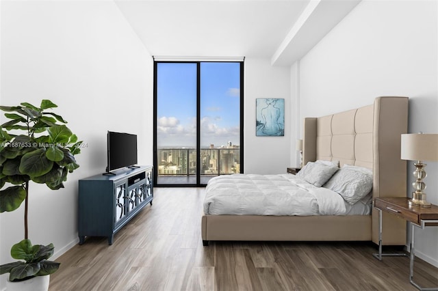 bedroom with access to outside, hardwood / wood-style floors, and a wall of windows