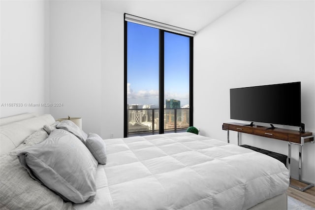 bedroom featuring hardwood / wood-style floors, access to outside, and a wall of windows