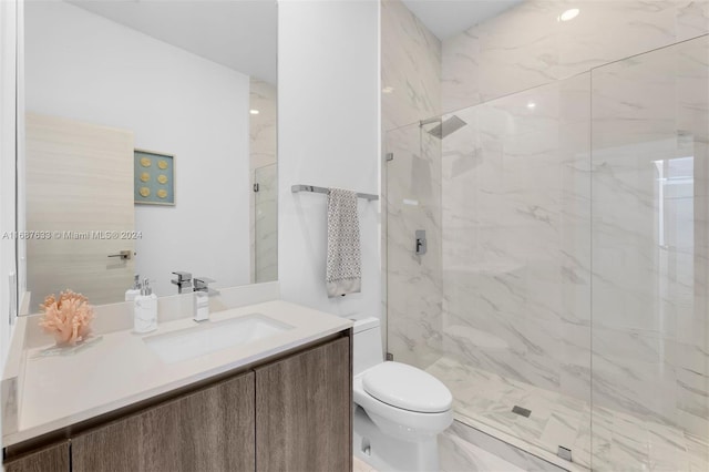 bathroom with a tile shower, vanity, and toilet