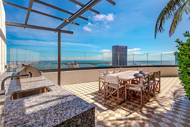 view of patio with a pergola, a water view, and sink