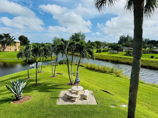 view of community featuring a lawn, a patio area, and a water view