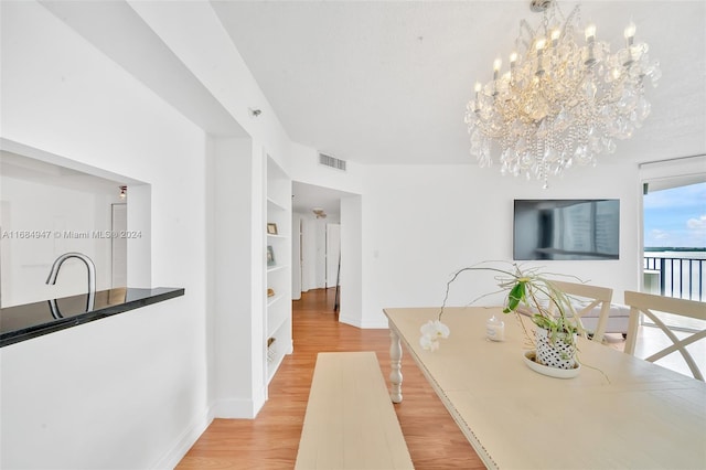 dining area with light hardwood / wood-style floors and a notable chandelier