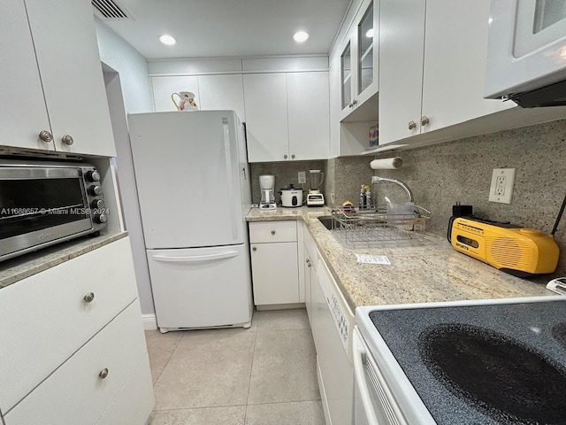 kitchen with light tile patterned floors, white appliances, white cabinetry, and sink