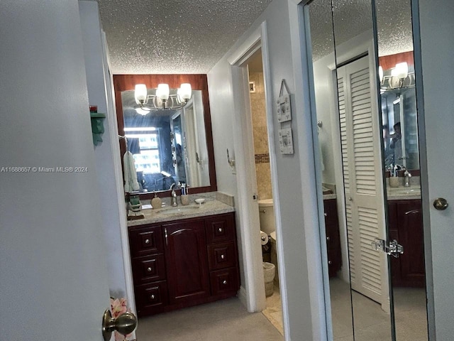 bathroom with vanity, a textured ceiling, toilet, and an inviting chandelier