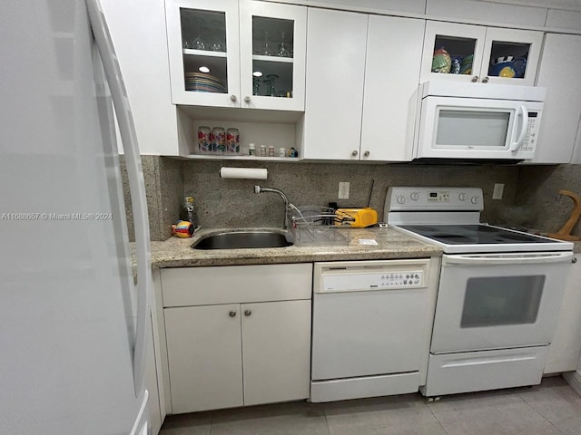 kitchen featuring sink, tasteful backsplash, light tile patterned floors, white appliances, and white cabinets