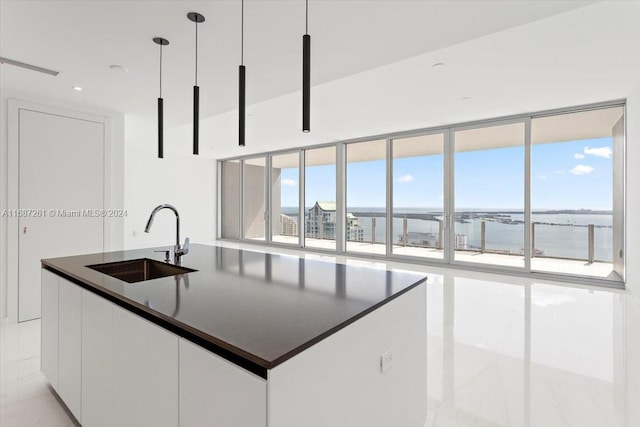 kitchen with white cabinets, a wealth of natural light, sink, and a kitchen island with sink