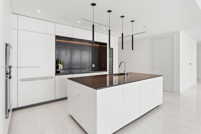 kitchen with white cabinetry, pendant lighting, sink, and an island with sink