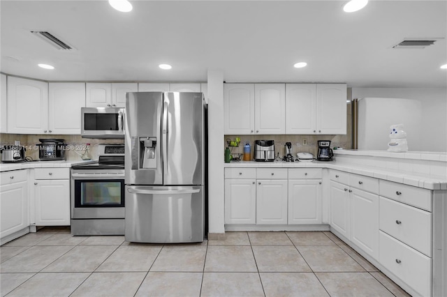 kitchen with light tile patterned flooring, white cabinetry, backsplash, and appliances with stainless steel finishes