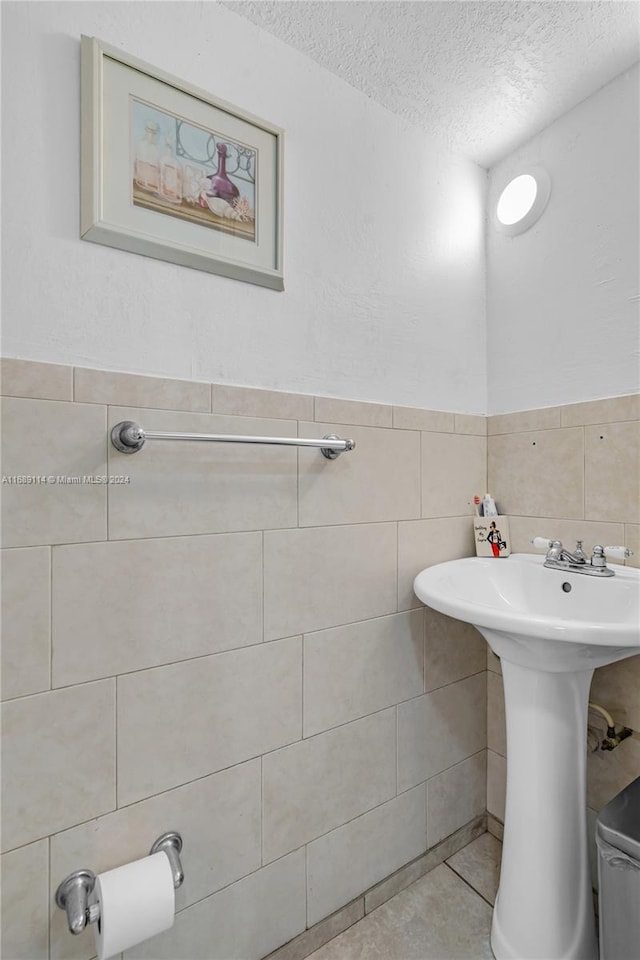 bathroom with sink, tile walls, a textured ceiling, and tile patterned floors