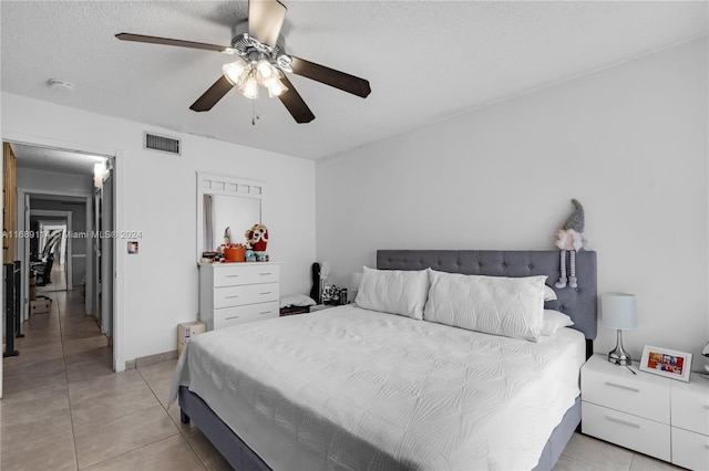 tiled bedroom with a textured ceiling and ceiling fan