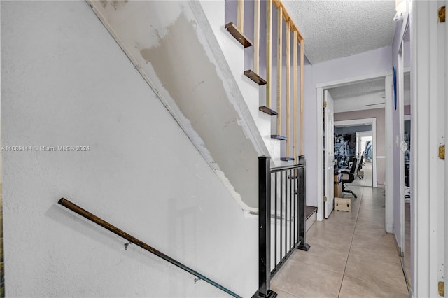 staircase with a textured ceiling and tile patterned floors