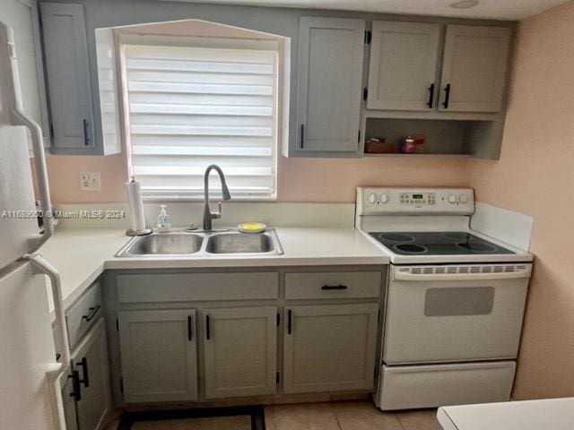 kitchen with gray cabinetry, white appliances, sink, and light tile patterned floors