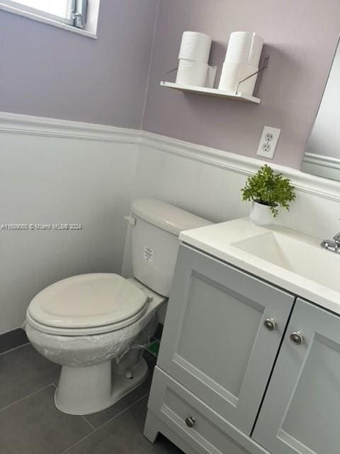 bathroom with toilet, vanity, and tile patterned floors