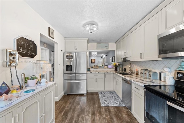 kitchen with white cabinetry, sink, appliances with stainless steel finishes, dark hardwood / wood-style floors, and backsplash