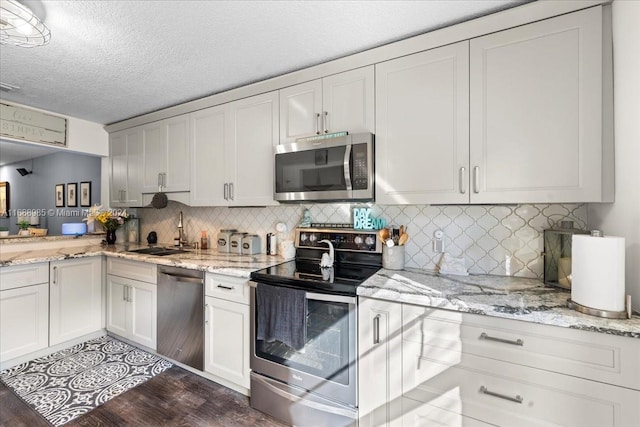 kitchen featuring stainless steel appliances, white cabinetry, sink, a textured ceiling, and dark wood-type flooring