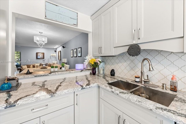 kitchen featuring white cabinetry, a textured ceiling, sink, and tasteful backsplash