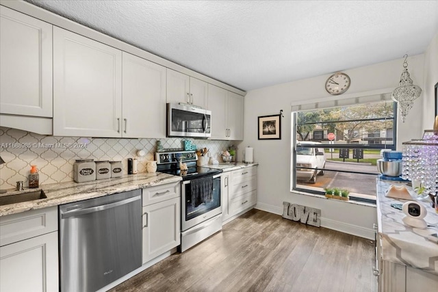 kitchen with white cabinetry, light wood-type flooring, stainless steel appliances, and decorative backsplash