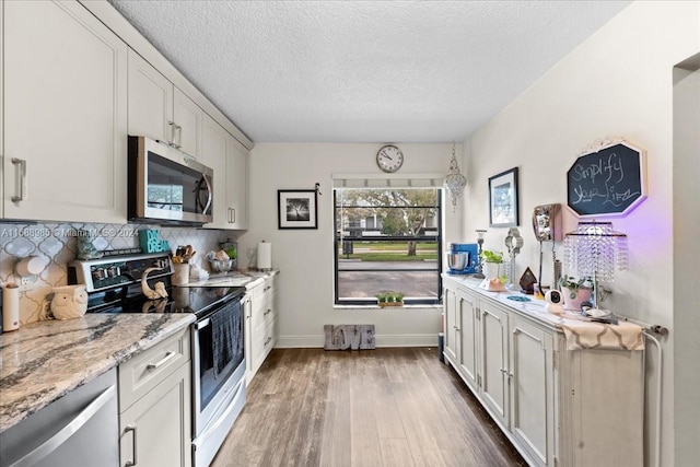 kitchen with light stone counters, white electric range oven, white cabinets, hardwood / wood-style floors, and decorative backsplash