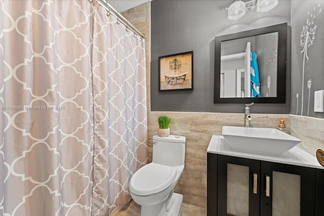 bathroom featuring vanity, toilet, and tile walls