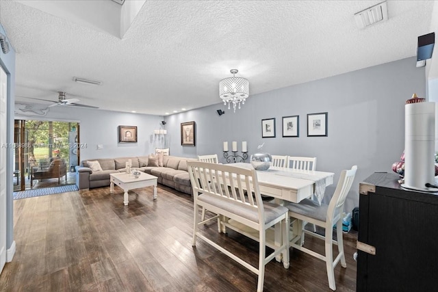 dining room with a textured ceiling, wood-type flooring, and ceiling fan with notable chandelier