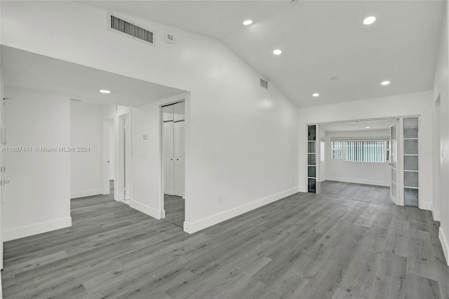 empty room featuring high vaulted ceiling and light wood-type flooring