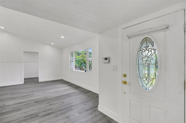 entrance foyer featuring a textured ceiling, vaulted ceiling, and light hardwood / wood-style flooring