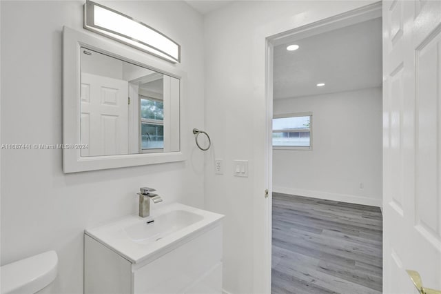 bathroom with wood-type flooring, vanity, and toilet