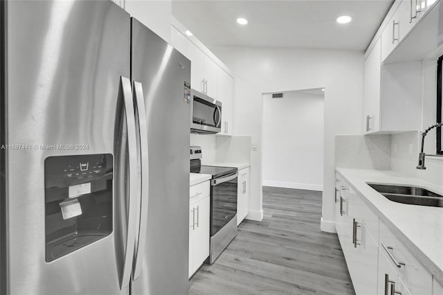 kitchen with white cabinetry, appliances with stainless steel finishes, sink, and light wood-type flooring