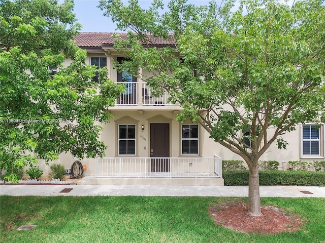 view of front of house with a balcony and a front yard