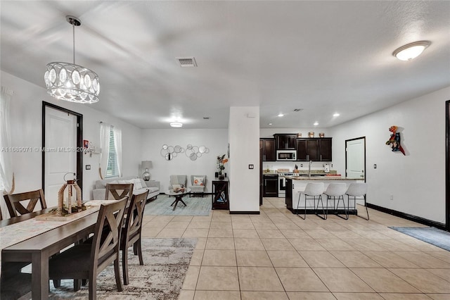 dining area featuring light tile patterned flooring, sink, and a notable chandelier