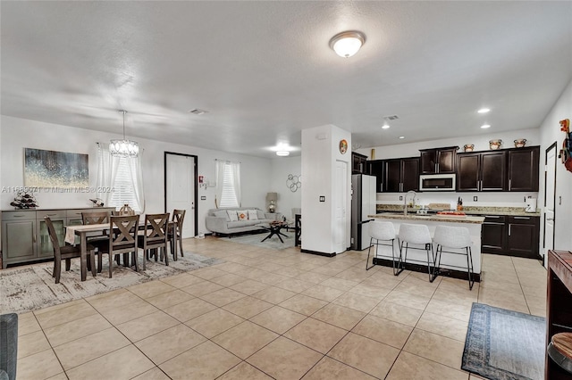 kitchen with sink, appliances with stainless steel finishes, a breakfast bar area, an island with sink, and hanging light fixtures