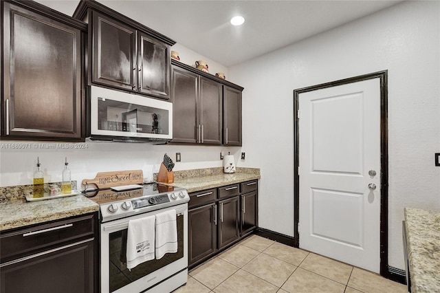 kitchen featuring dark brown cabinetry, appliances with stainless steel finishes, light tile patterned floors, and light stone countertops