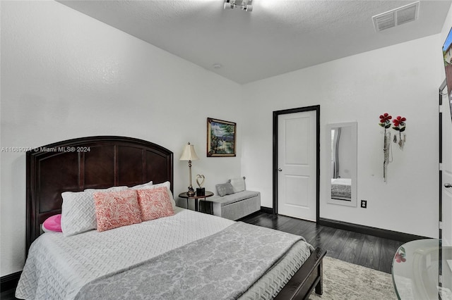 bedroom with a textured ceiling and dark hardwood / wood-style flooring